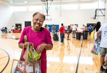 Lady smiling with a bag of goodies at the Health Expo