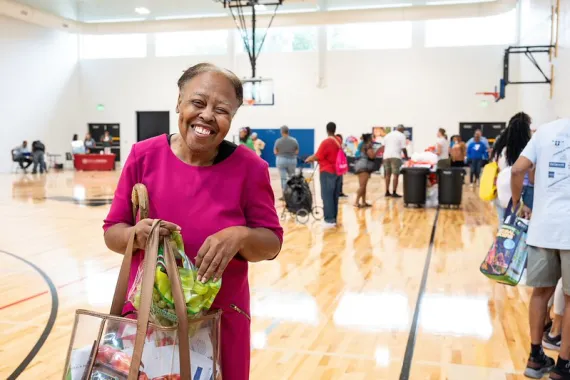 Lady smiling with a bag of goodies at the Health Expo