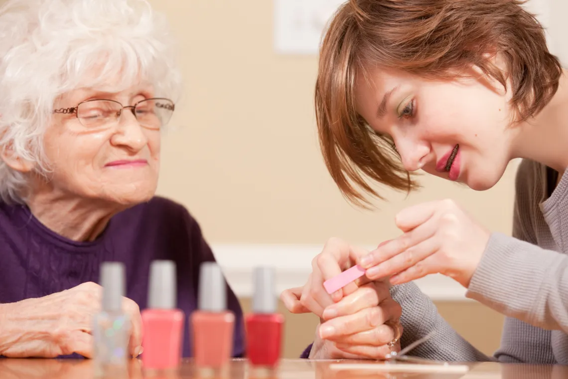 Teen painting the nails of an elderly lady